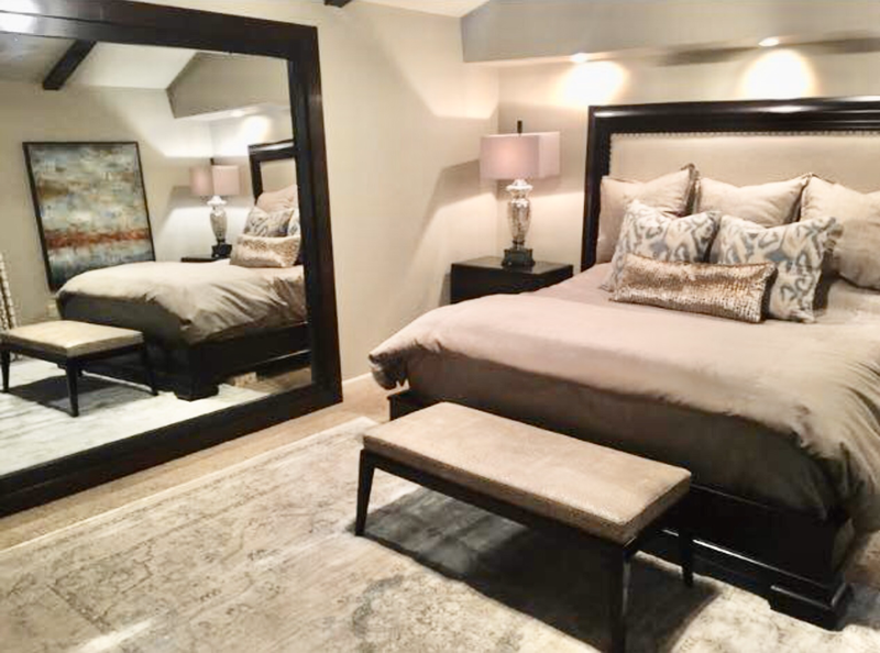king size wood bed and bench with large wood framed floor mirror