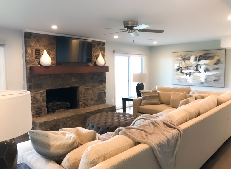 tan sectional sofa and grey artwork with stone fire place living area 