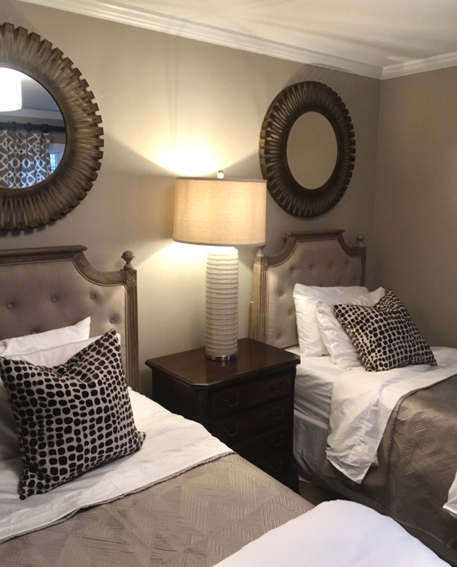 guest bedroom with twin beds and tow round mirrors and white lamp 